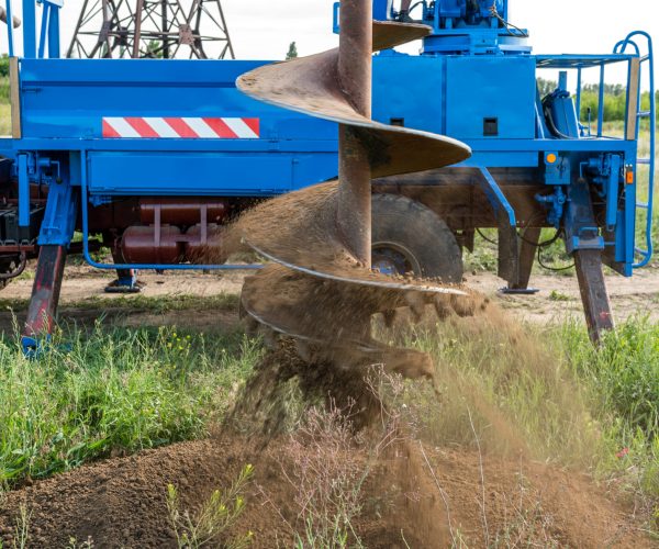 Tracer tractor with auger for soil drilling for piles installation during construction of buildings and structures